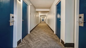 A long, narrow hallway with blue walls and white trim, leading to a door at the end.