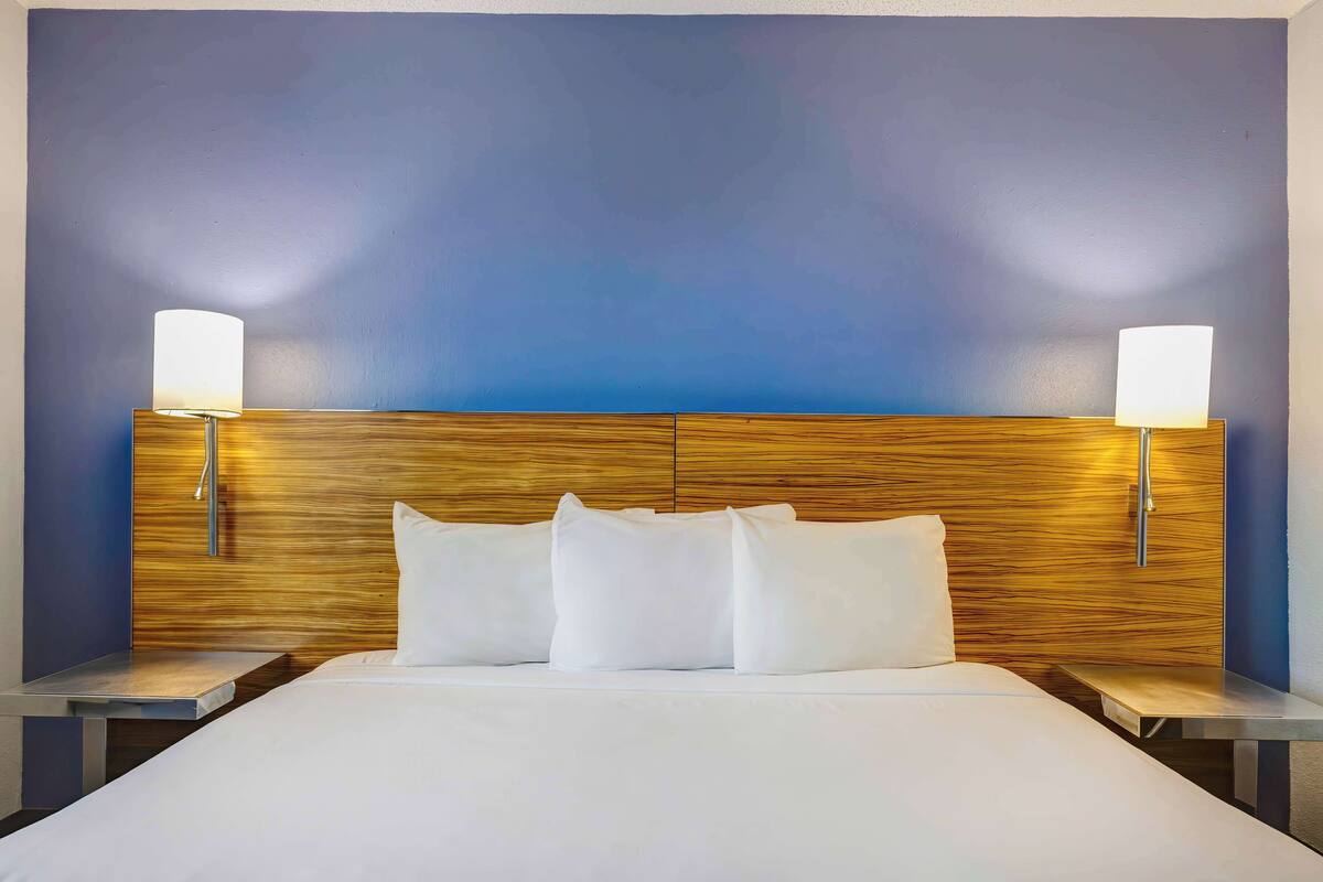 A hotel room with a large bed, two bedside tables, and a wooden headboard.