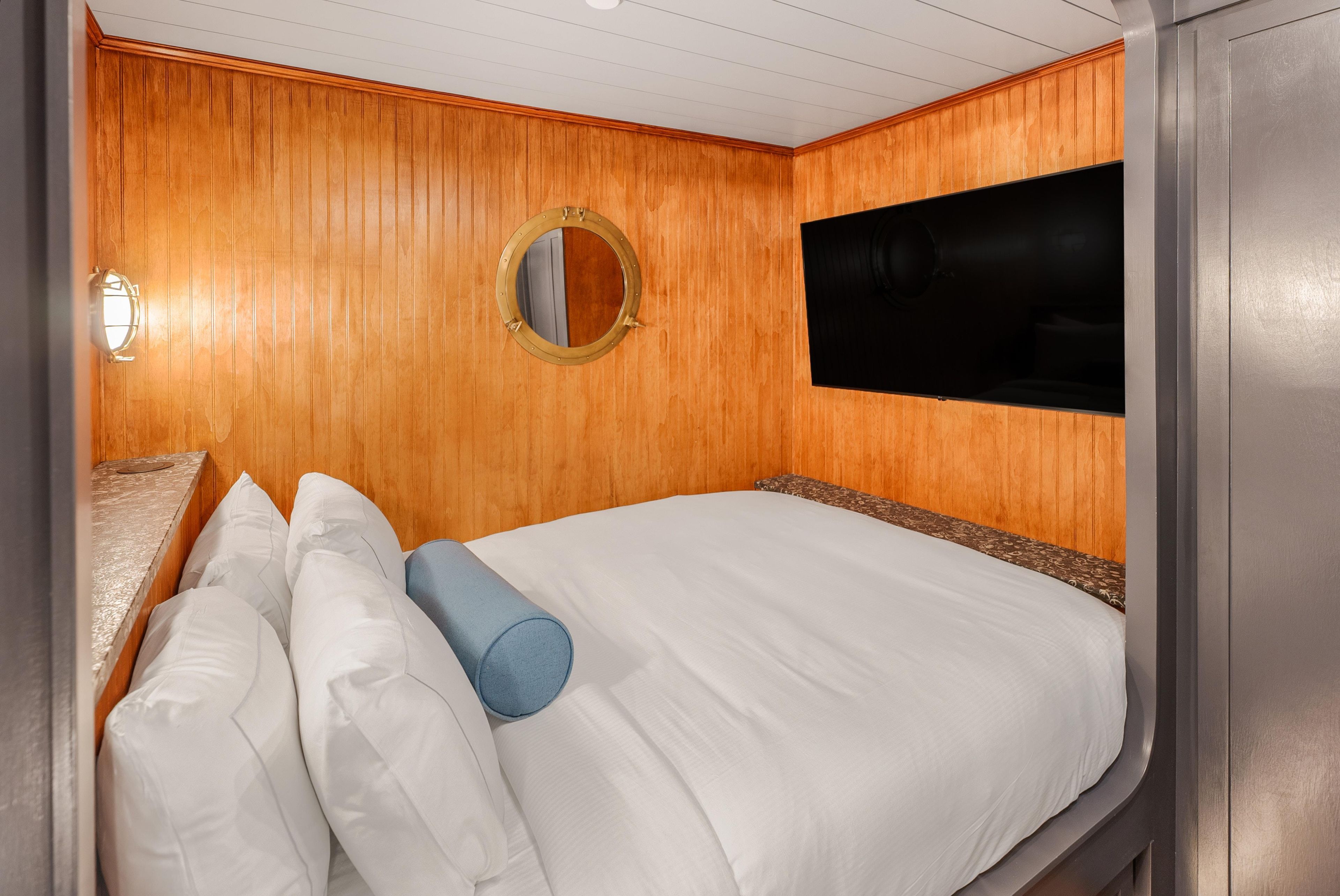 Una habitación con una cama, un espejo redondo y un televisor.
