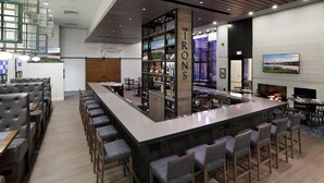 A bar area with a high bar counter, stools, and a fireplace. - Hilton Mystic (Mystic)