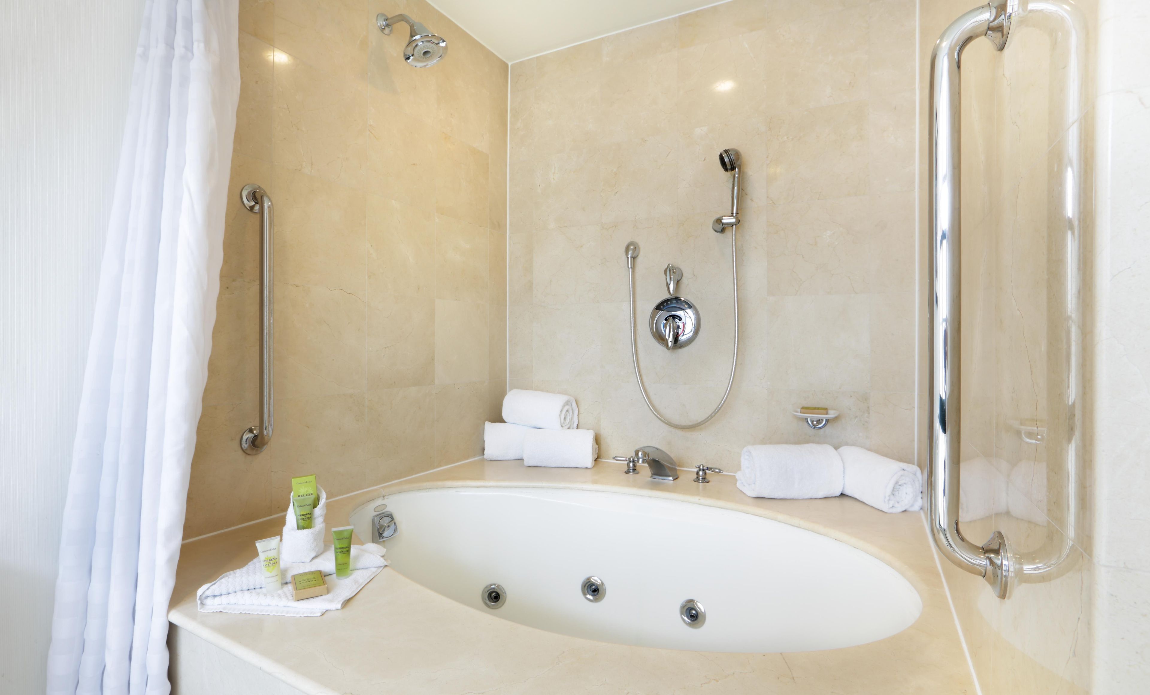 A bathroom with a bathtub, a shower, and a toilet. There are towels and toiletries on the counter.
