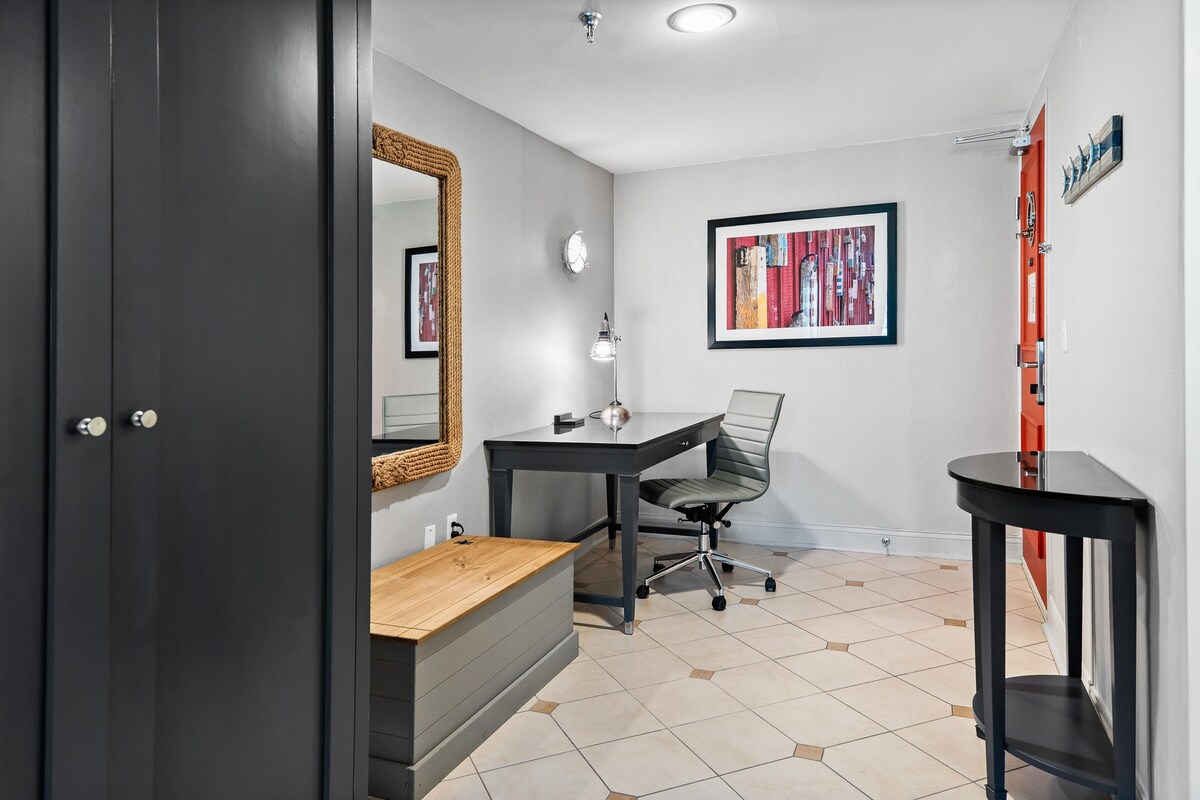 Ein Zimmer mit Schreibtisch, Stuhl und Spiegel an der Wand.