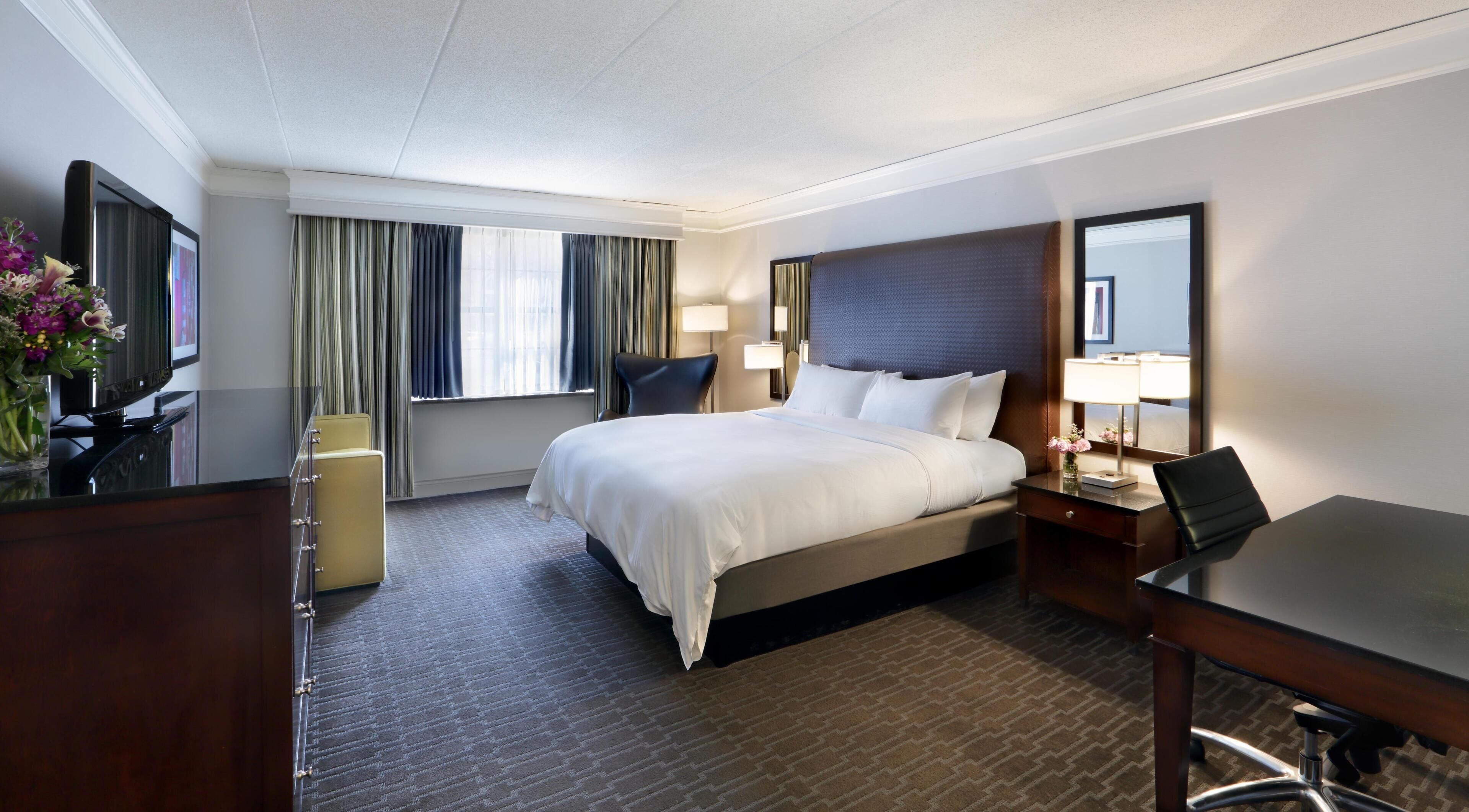 Une chambre d’hôtel équipée d’un lit, d’un bureau, d’une chaise et d’un téléviseur.