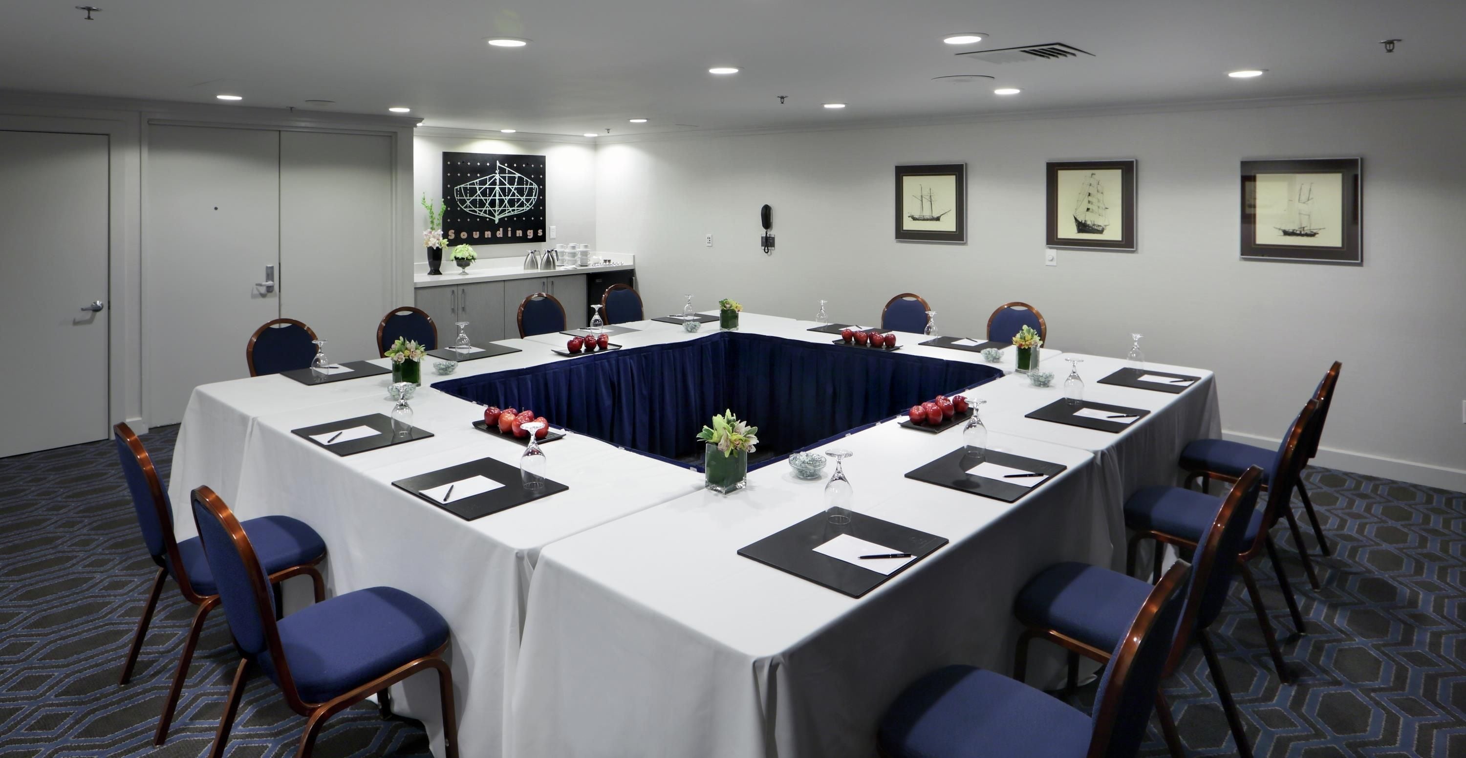Une salle de conférence avec une longue table, des chaises et des tableaux encadrés accrochés aux murs.