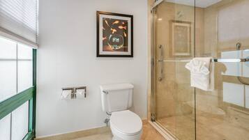 A modern bathroom with a toilet, a glass shower enclosure, and a framed artwork on the wall.
