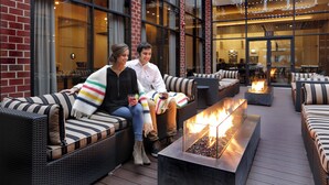 A couple sitting on a striped sofa with a fire feature in the center. - Hilton Mystic (Mystic)