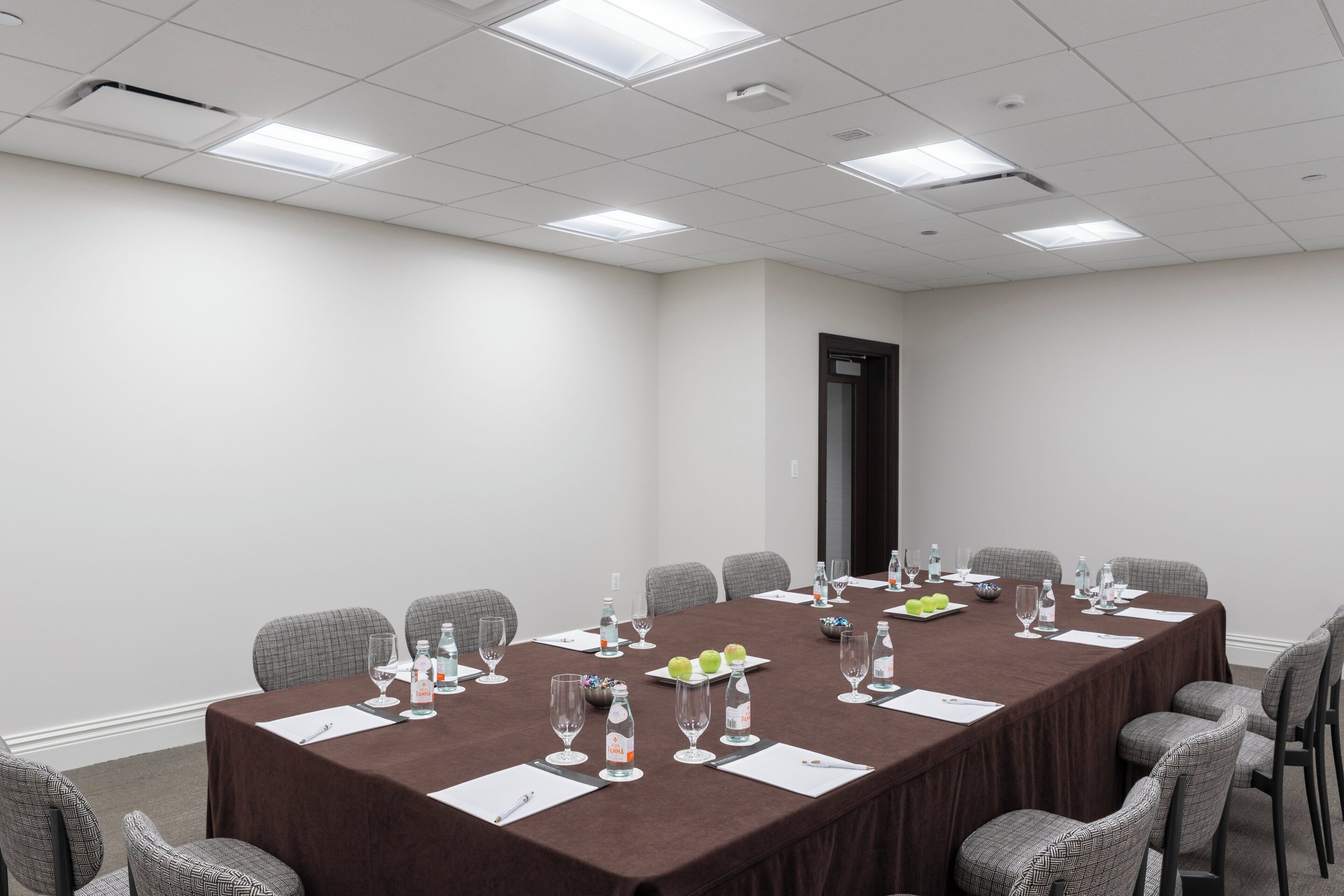 A conference room with a long table, chairs, and meeting supplies.