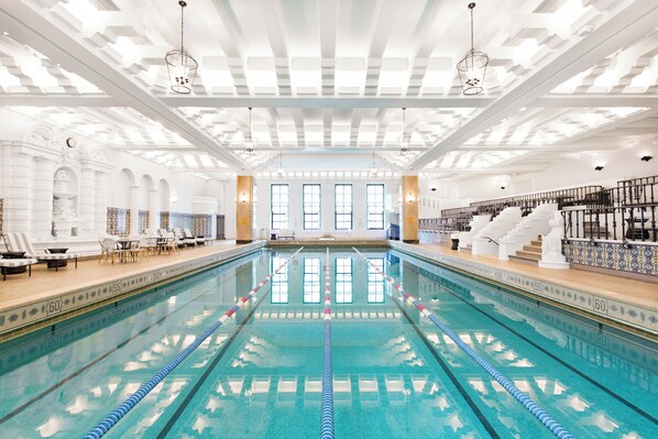 Relax by the long, clear water pool with lane dividers, surrounded by a seating area with lounge chairs and tables.
