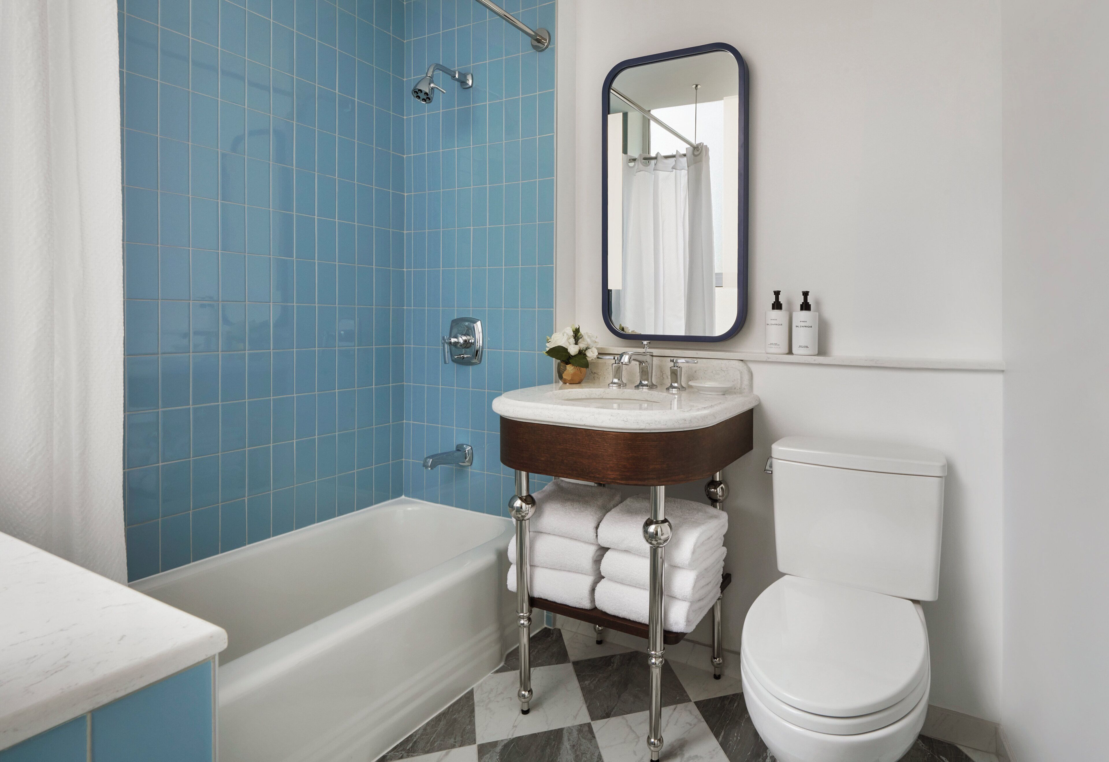 Un baño con bañera, lavamanos con espejo e inodoro.