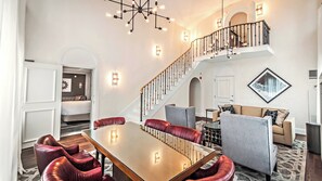 Un vaste espace de vie comprenant une table à manger, des fauteuils en cuir rouge, un escalier et une vue sur la chambre à coucher.