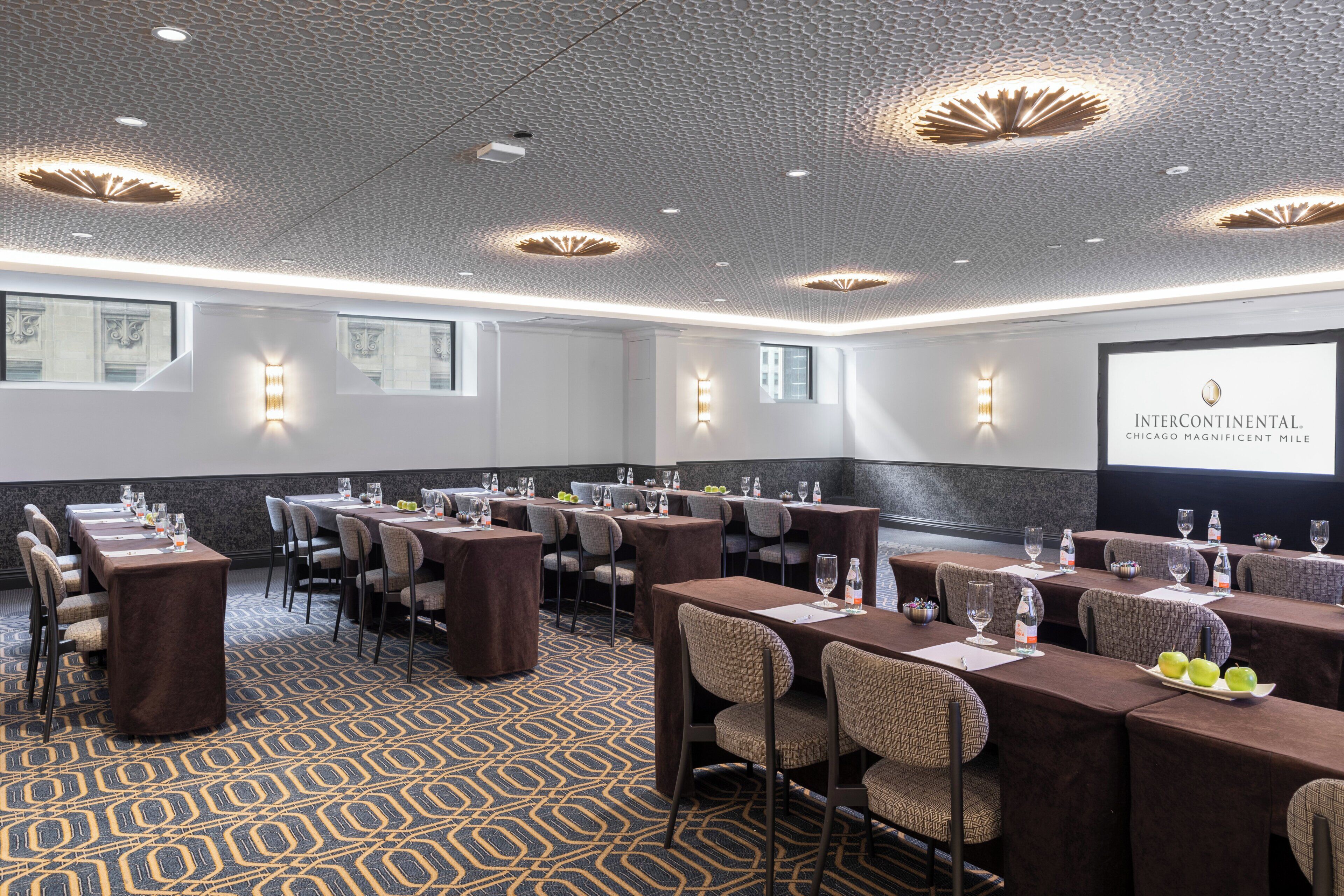 A conference room with tables, chairs, and a presentation screen.