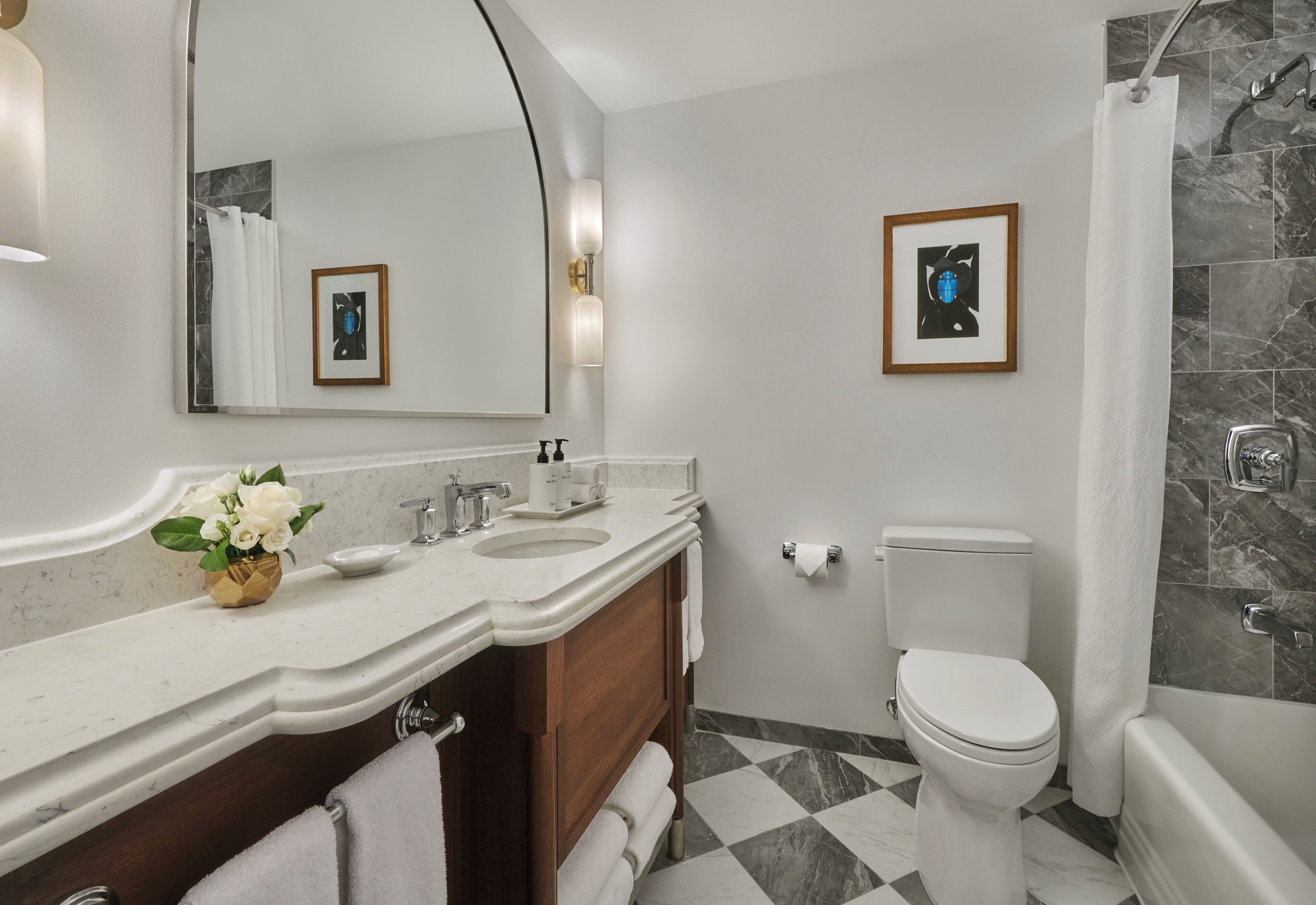 A modern bathroom with a marble sink, a toilet, and a shower.