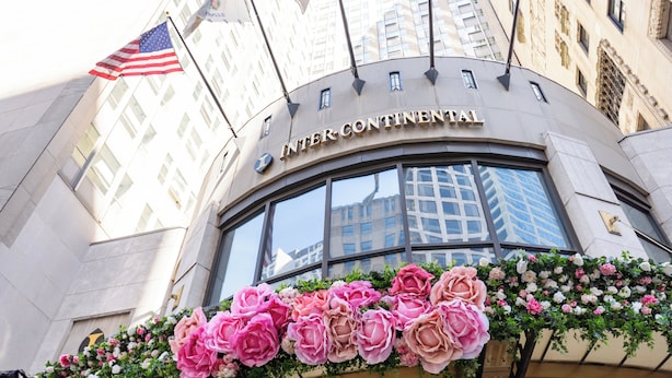 Hotel Intercontinental's facade med et stort amerikansk flag og et blomsterarrangement.