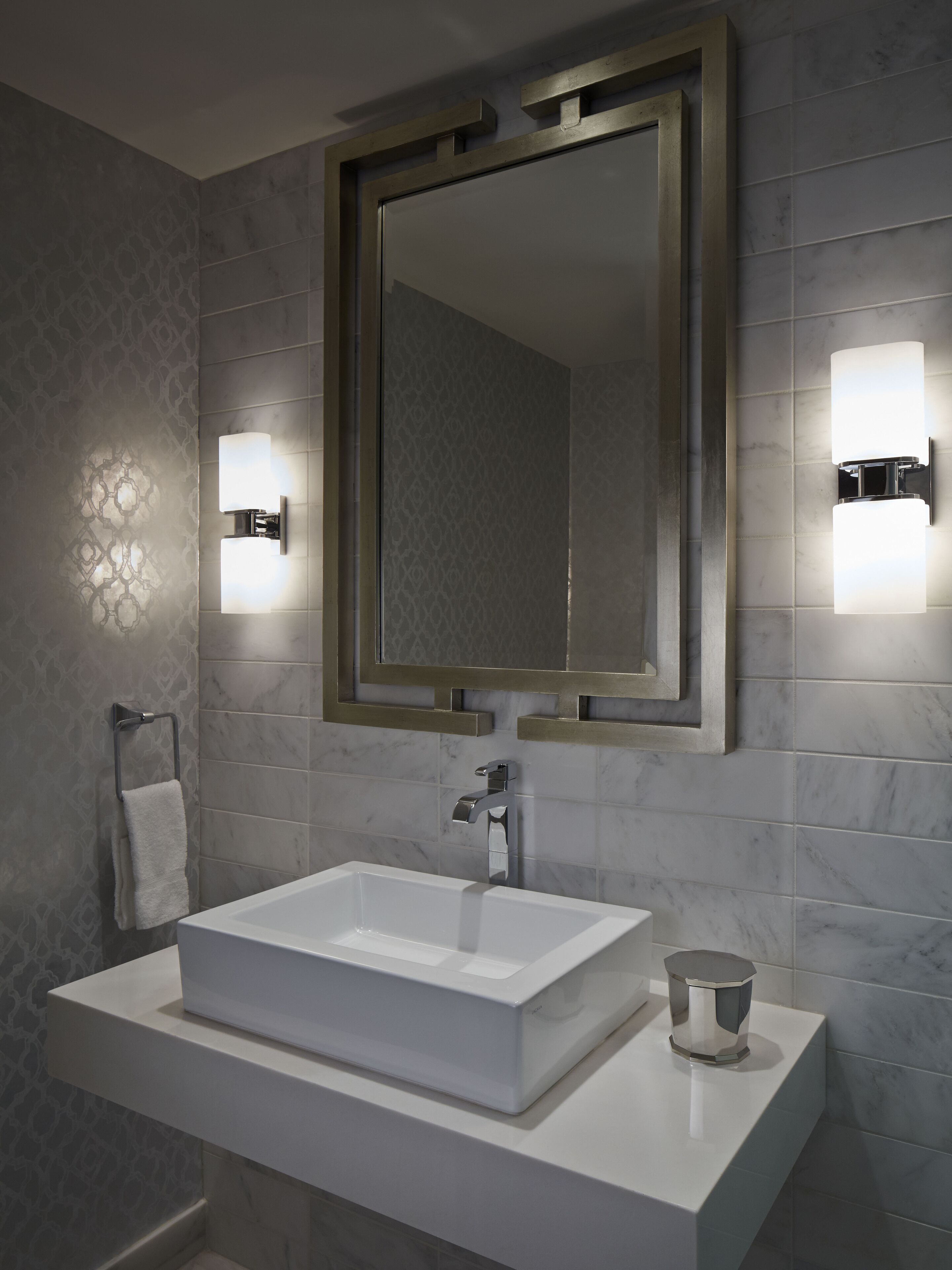 Un baño moderno con un lavabo rectangular, un espejo grande y dos luces fijadas a la pared.