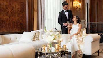 Quarto luxuoso com um sofá branco, uma mesa redonda com velas e um candelabro.