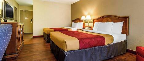 Habitación de hotel con dos camas, televisión, escritorio y lámpara.