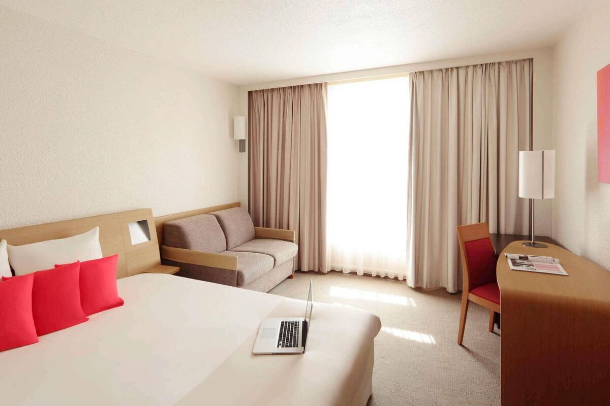 Een hotelkamer met een bed, een slaapbank, een bureau en een stoel.