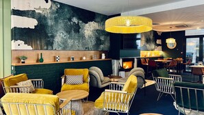 A modern lounge area with yellow and grey furniture, a fireplace, and a large abstract wall art piece. - Novotel Paris Pont De Sevres (Sevres)