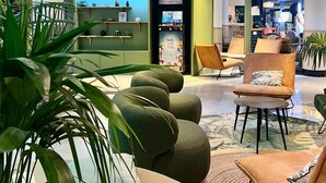 A hotel lobby with seating areas, a reception desk, and a minibar. - Novotel Paris Pont De Sevres (Sevres)