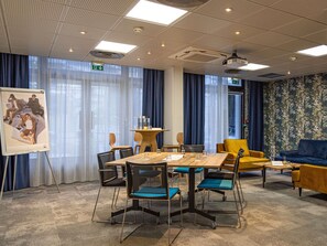 A conference room with a large table, chairs, a projector screen, and a patterned wall. - Novotel Paris Pont De Sevres (Sevres)