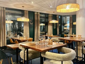 A restaurant interior with wooden tables, woven chairs, and hanging lamps. - Novotel Paris Pont De Sevres (Sevres)