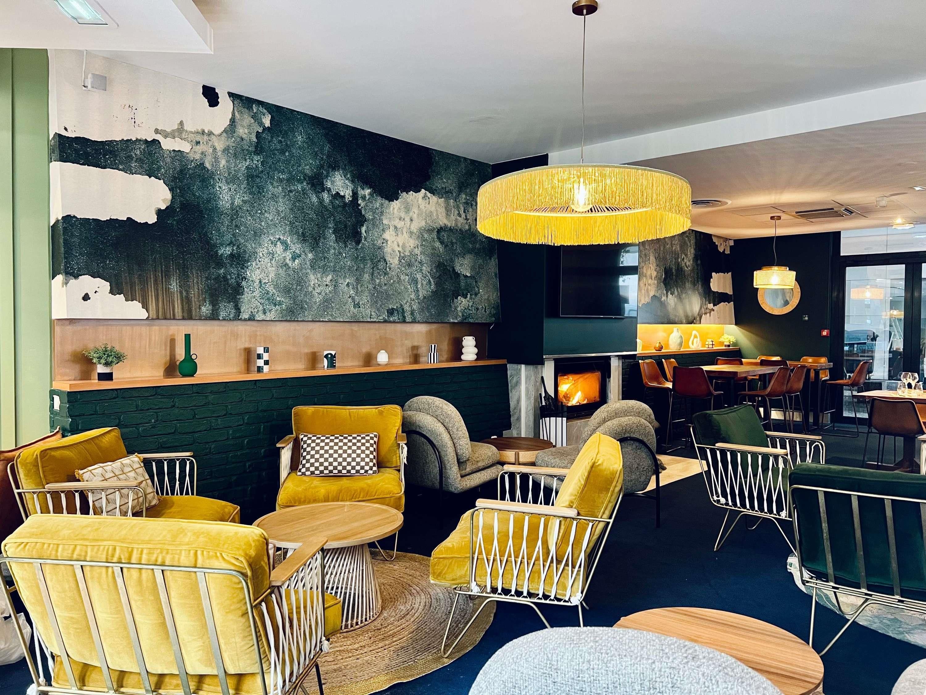 A modern lounge area with yellow and grey furniture, a fireplace, and a large abstract wall art piece.