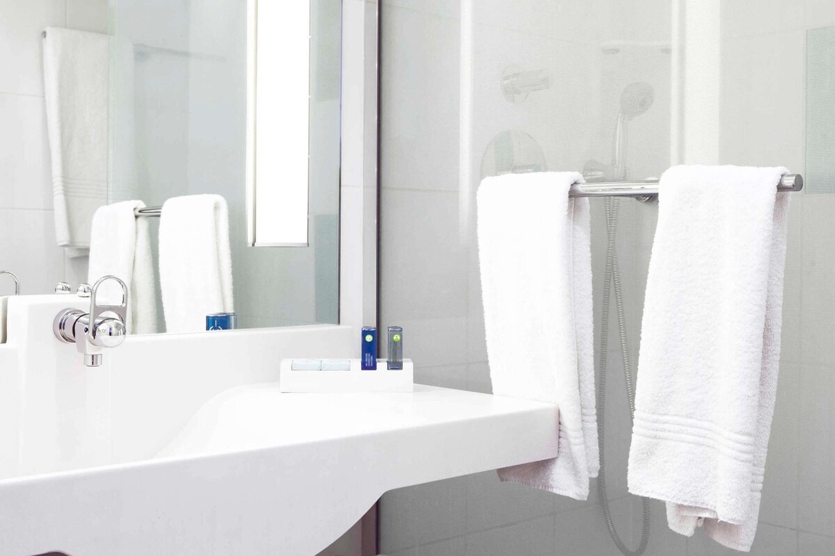 A modern bathroom with a white sink, a mirror, and two towels hanging on a towel rack.