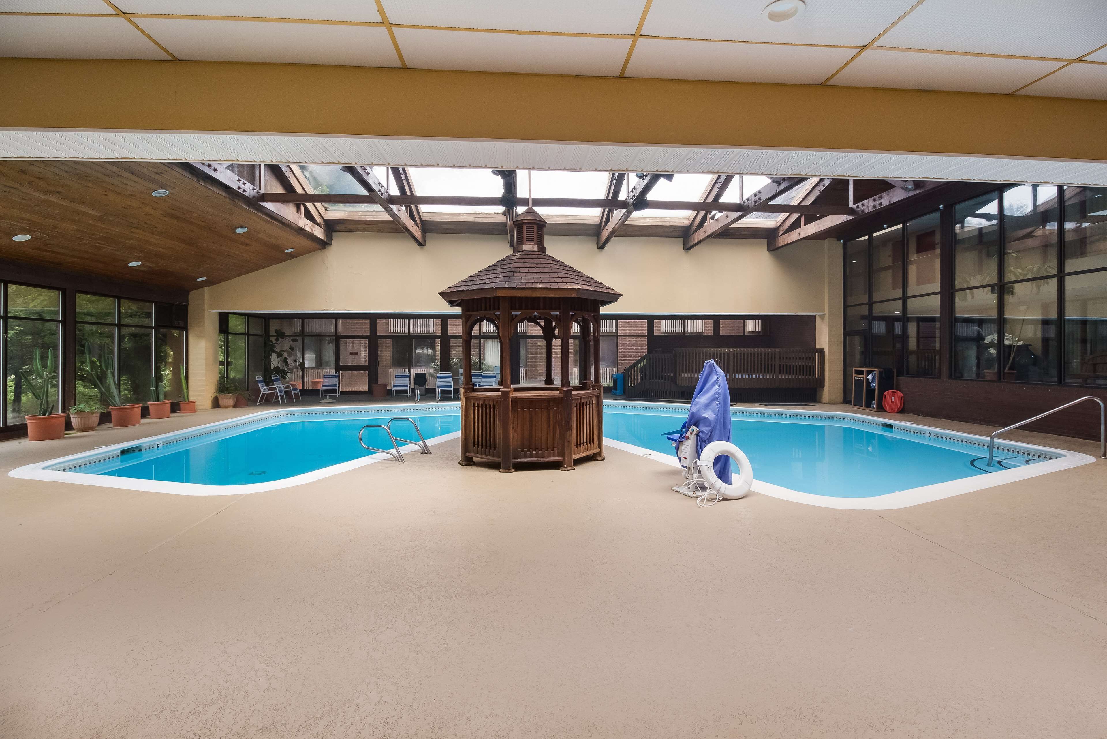 Una piscina interior con un quiosco de madera, plantas en macetas y un flotador salvavidas.