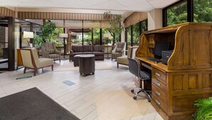 A spacious room with a large desk, comfortable seating, and large windows offering a view of greenery. - Best Western Braddock Inn (Cumberland)