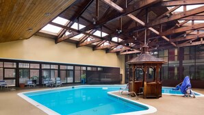 An indoor swimming pool with a wooden gazebo, lounge chairs, and a view of the outside through large windows. - Best Western Braddock Inn (Cumberland)