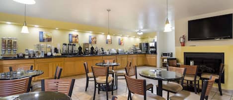 A modern kitchen with wooden cabinets, a central island, and a flat-screen TV mounted on the wall.