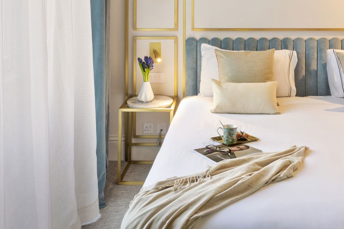 Een hotelkamer met een bed, een kaptafel met spiegel en een nachtkastje met een bloevas.