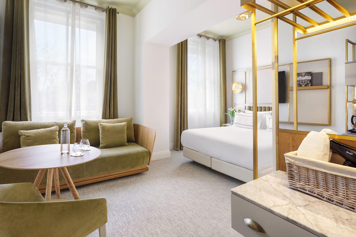 Ein Hotelzimmer mit einem Bett, einem Sofa, einem runden Tisch und einem kleinen Schreibtisch.