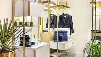 A modern, well-lit walk-in closet with a mirrored wardrobe, a vanity with a marble countertop, and a potted plant.
