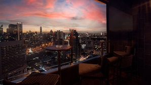 A cityscape view from a balcony with high-rise buildings and a sunset sky. - The Landmark Bangkok (Bangkok)