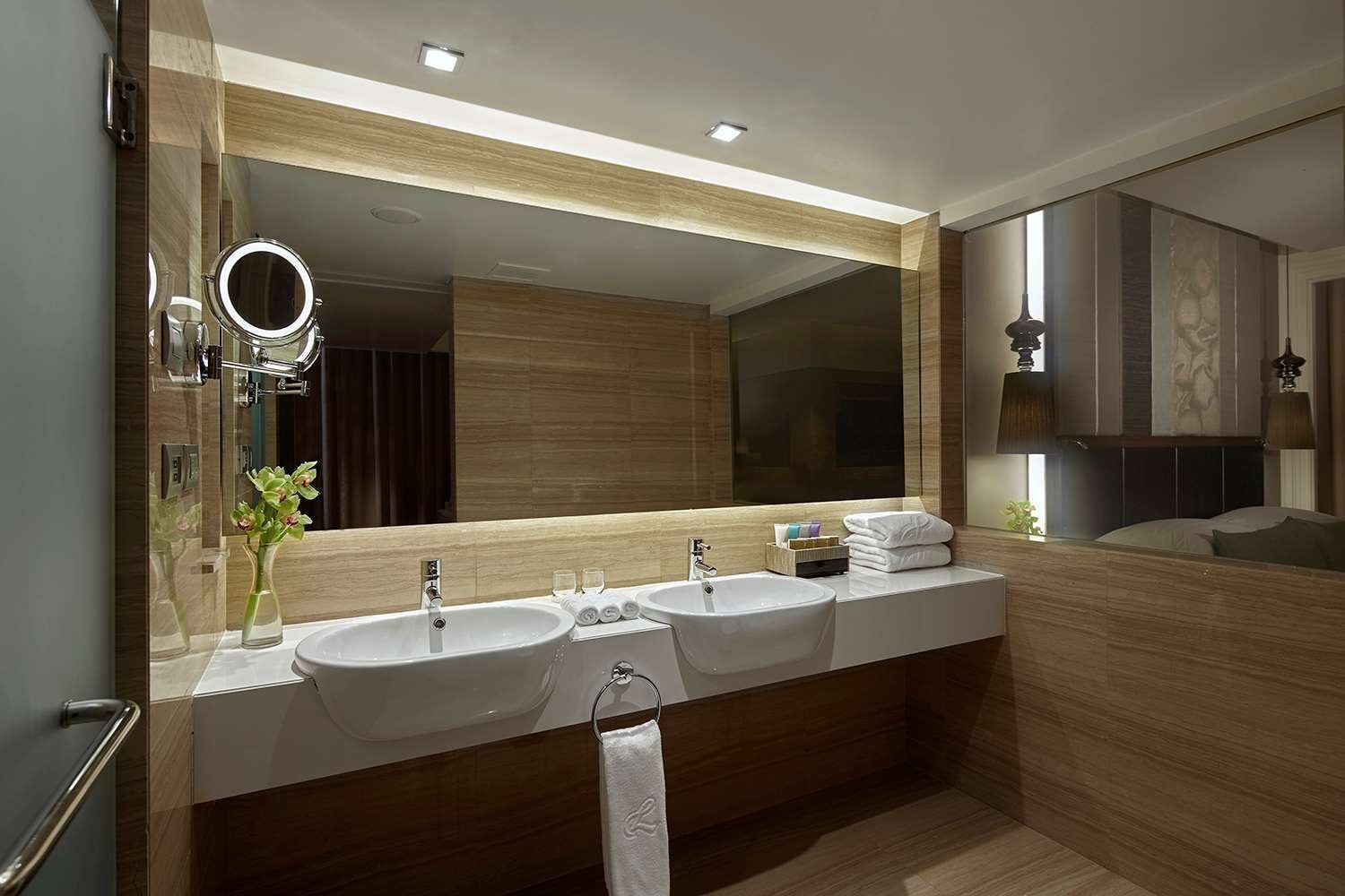 Un baño moderno con dos lavamanos, un espejo grande y un tocador con artículos de aseo.