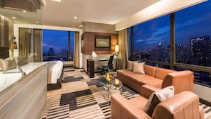 A modern hotel room with a large city view, a desk, a sofa, and a bed. - The Landmark Bangkok (Bangkok)
