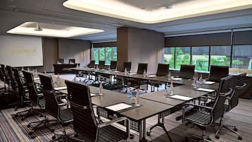 A conference room with a long table, multiple chairs, and a projector screen displaying "The Landmark Bangkok".