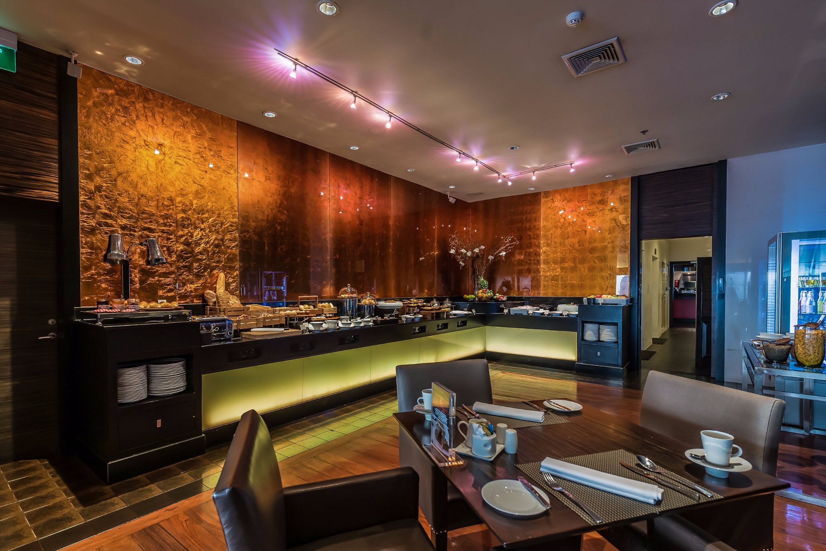 Un restaurant moderne doté d’un comptoir central, d’un espace salon et d’un mur décoratif.