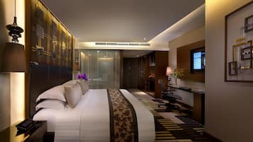 Una habitación de hotel moderna con una cama grande, un escritorio con computadora y un televisor montado en la pared.