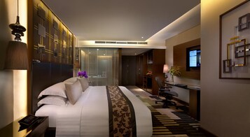 Una habitación de hotel moderna con una cama grande, un escritorio con computadora y un televisor montado en la pared.
