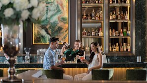 A bar area with a marble countertop, bar stools, and a large selection of liquor bottles on shelves. - The Landmark Bangkok (Bangkok)