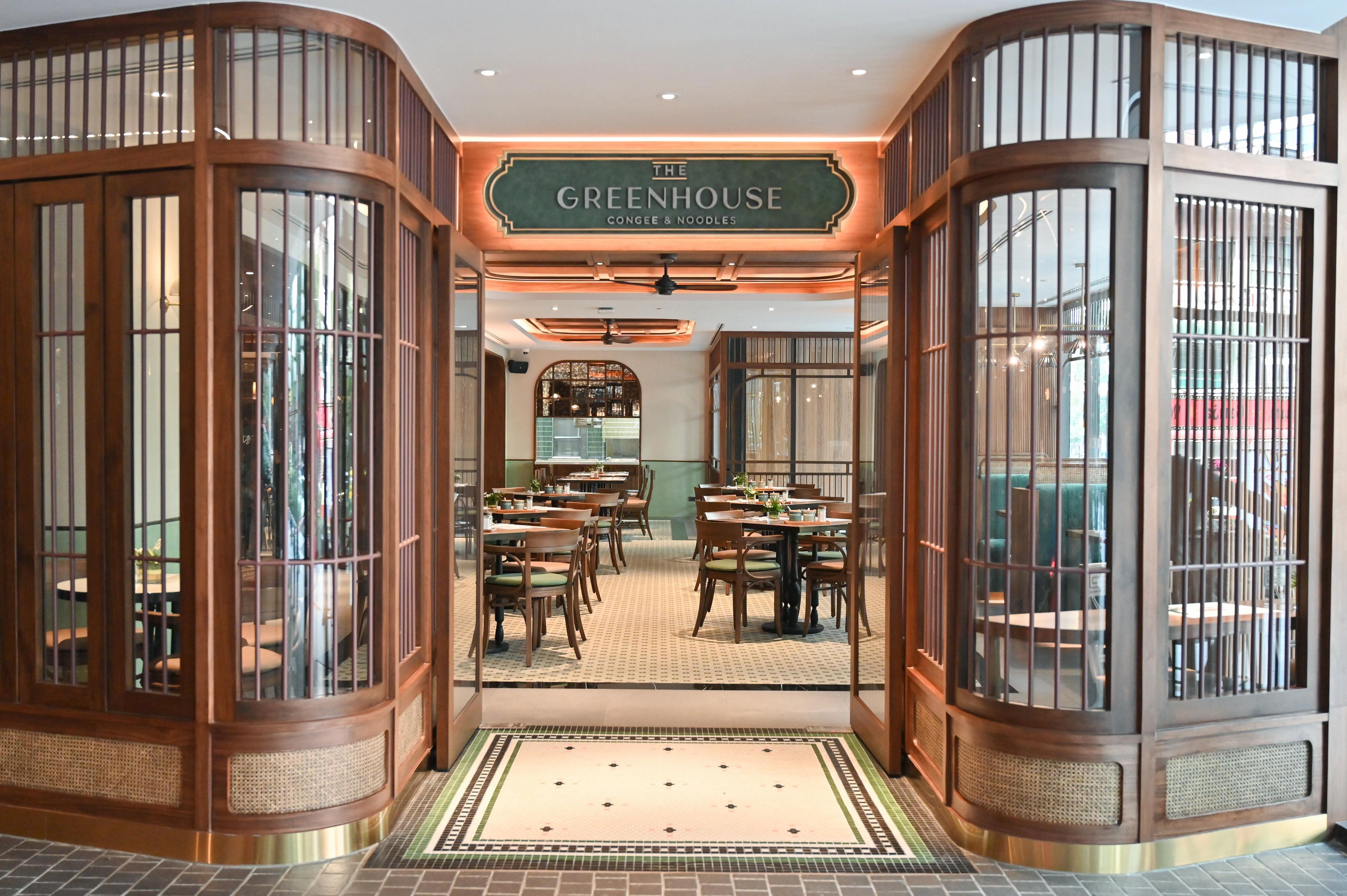 A restaurant interior with a sign reading 'The Greenhouse Congee & Noodles'.