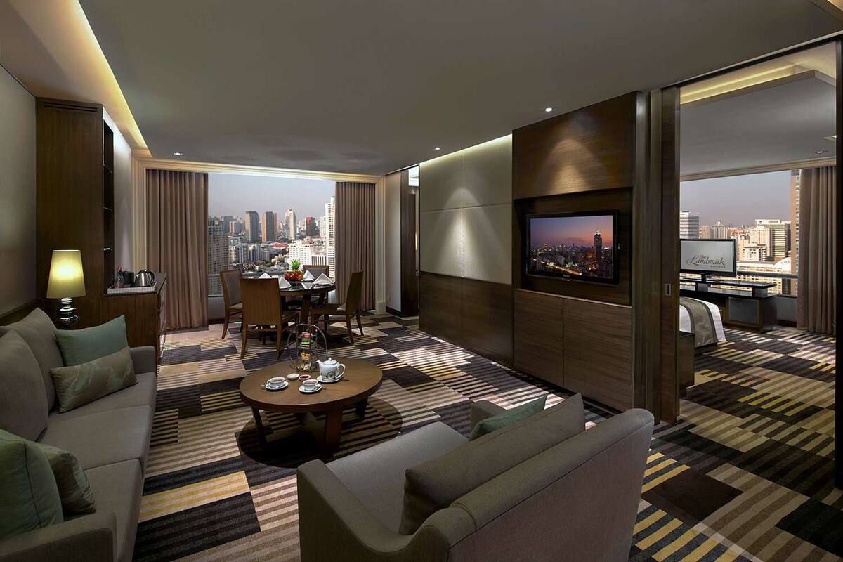 A modern hotel room with a city view, a dining area, a TV, and a cozy seating arrangement.