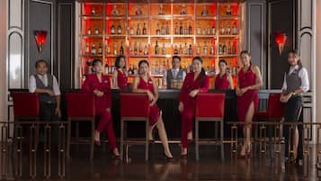 A bar area with a row of red bar stools and a bartender behind the bar.