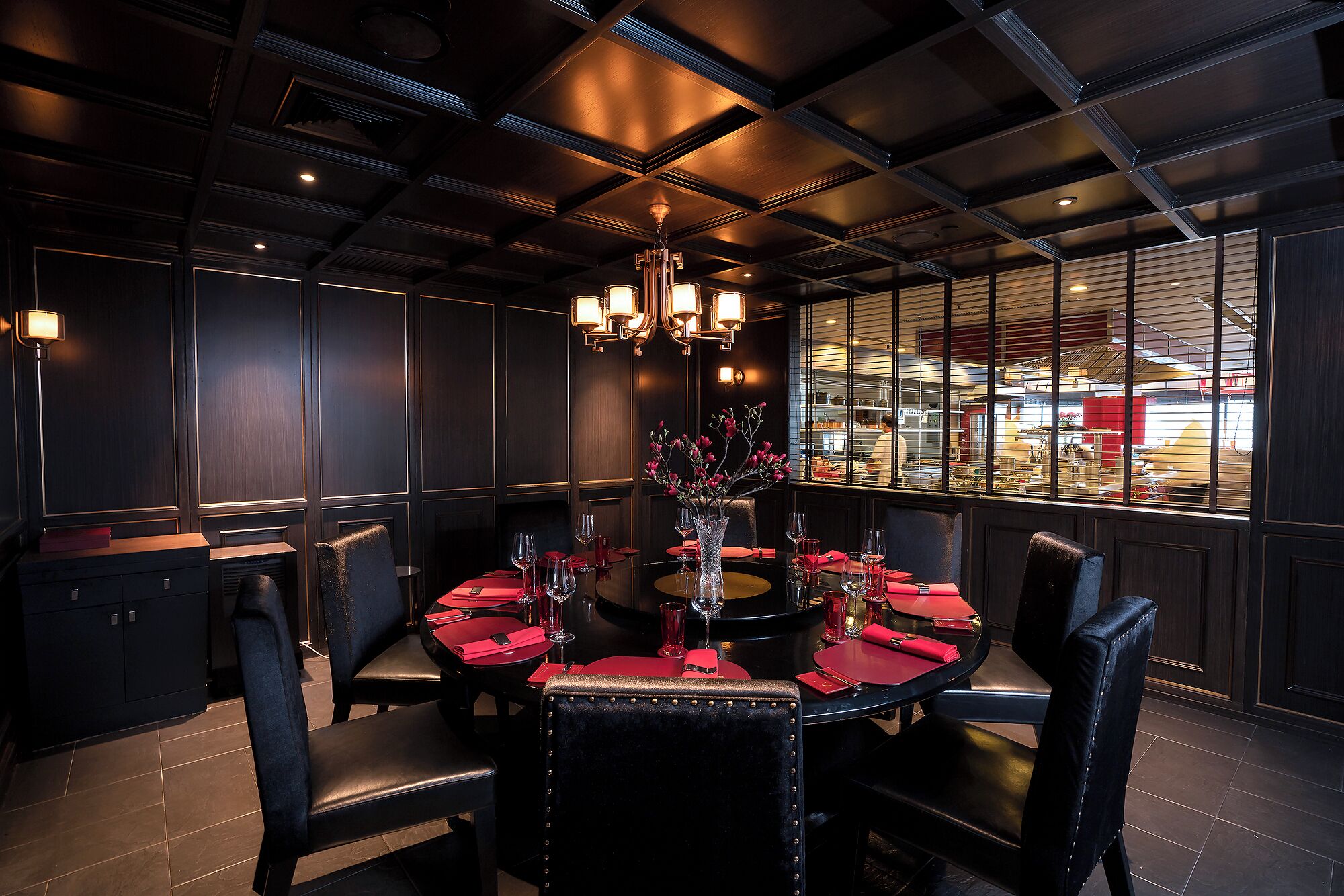 A dining area with a round table set for four, surrounded by black upholstered chairs.
