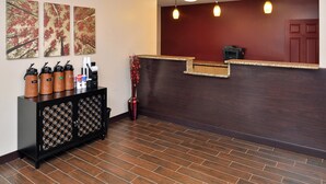 A reception area with a dark wooden counter, a coffee station with branded dispensers, and three framed artworks on the wall. - Red Roof Inn Marietta (Marietta)