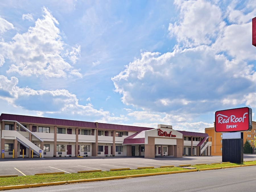 Un Red Roof Inn con un edificio de dos pisos, un estacionamiento y cielo despejado.