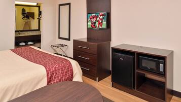 Una habitación de hotel con cama, cómoda, televisor y minibar.