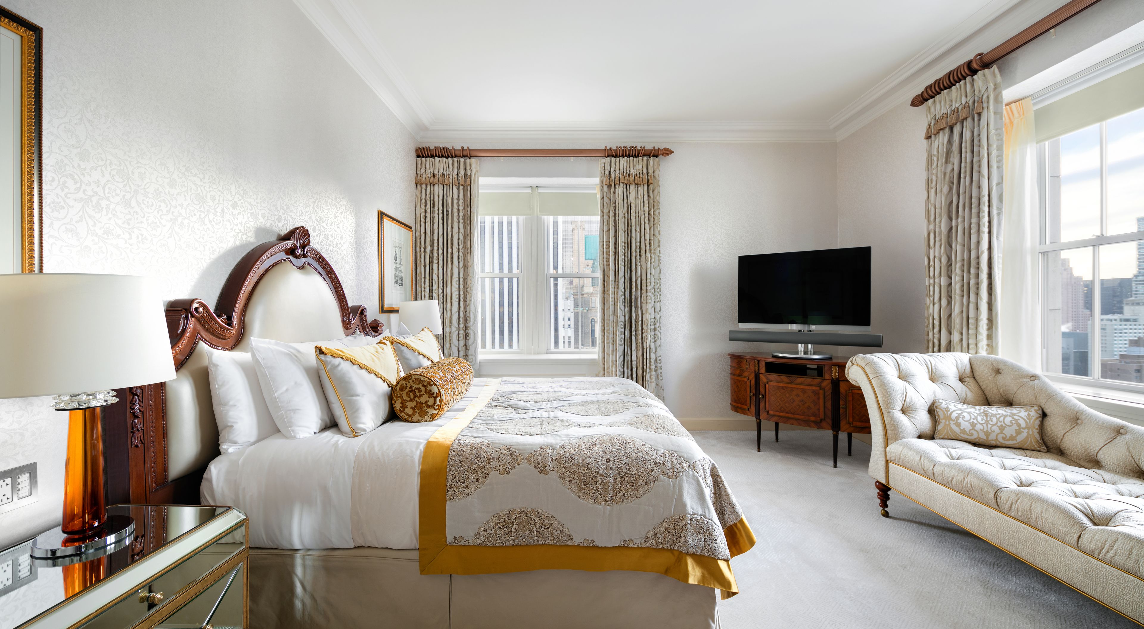 A hotel room with a large bed, a TV, a desk, and a chair.